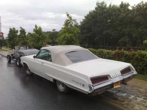 1991 Ford LTD Crown Victoria - A white 1967 Dodge Monaco convertible tows a hot rod trailer on a wet day.