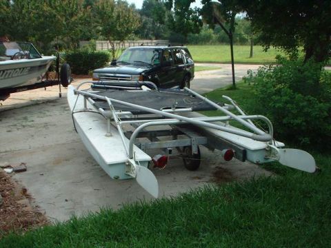 1996 Ford Taurus - A black SUV is parked in a driveway next to a boat on a trailer, with trees and grass in the background.