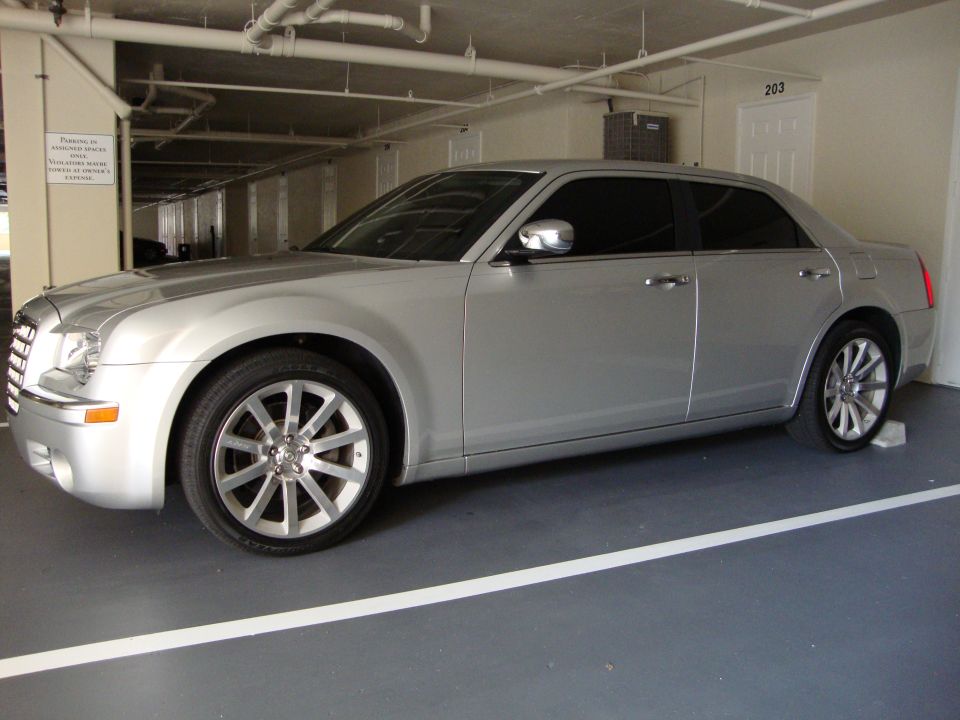 Silver sedan parked in a garage, 3/4 front view. The car has tinted windows and multi-spoke wheels