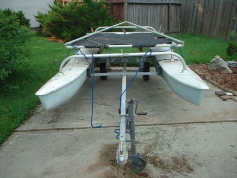 1996 Ford Taurus - A white catamaran hull sits on a trailer in a grassy yard.
