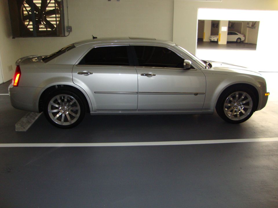 Silver sedan parked in a garage. Side view shows tinted windows and chrome wheels