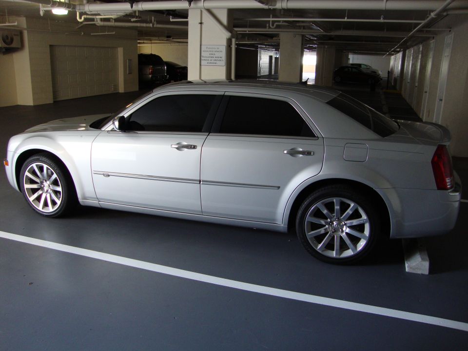 Silver Chrysler 300 parked in a garage. Side view shows tinted windows and multi-spoke wheels