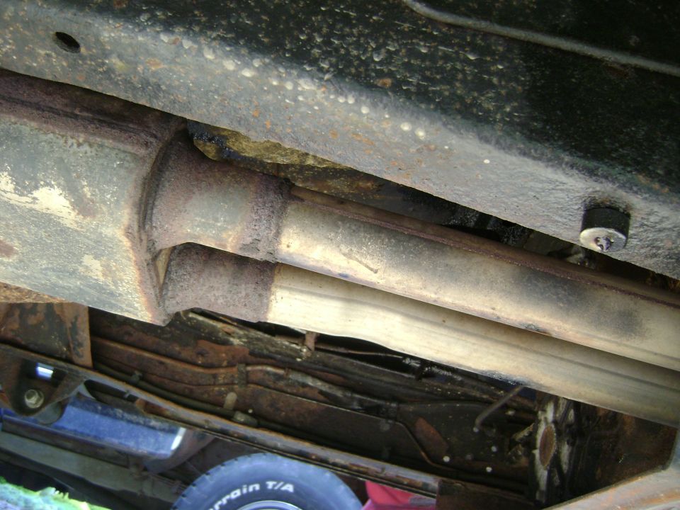 Undercarriage view of dual exhaust pipes and frame, with a tire visible