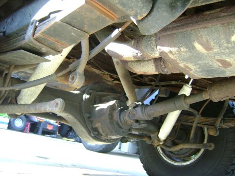 1979 Ford Bronco - The underside of a vehicle shows its rear axle, leaf springs, and shock absorbers.