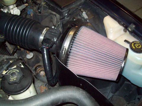 1999 Mercury Grand Marquis - Close-up view of an engine's air intake system, including a conical air filter and mass airflow sensor.