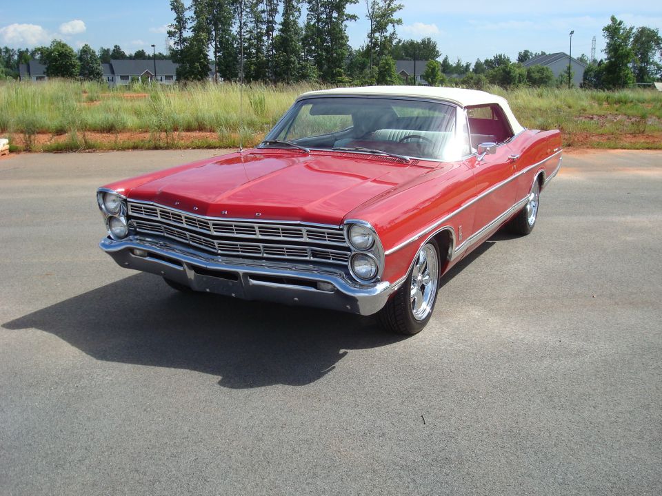 Red 1967 Ford Galaxie convertible with white top, front 3/4 view in a paved lot