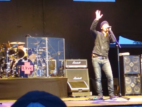 1996 Ford Bronco - A musician performs live on stage with a drum set and amplifiers, raising a hand.