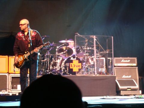 1996 Ford Bronco - A live music performance with a guitarist and drummer on stage, accompanied by amplifiers.