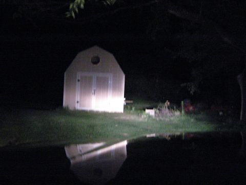 2000 Mercury Grand Marquis - A shed is illuminated by bright lights, with its reflection visible in the dark water below.