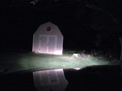 2000 Mercury Grand Marquis - A shed is lit by headlights at night, with its reflection visible in the dark water.