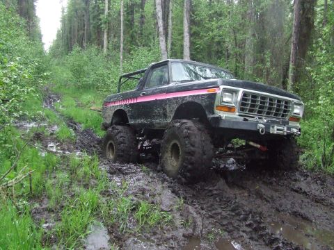 1990 Ford Bronco - This lifted Ford Bronco navigates a muddy, wooded path with large, aggressive tires.