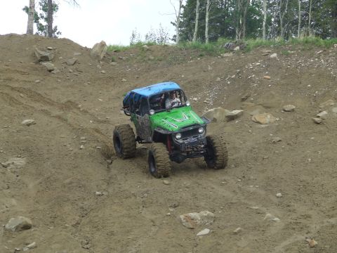 1990 Ford Bronco - An off-road vehicle navigates a steep, rocky incline on a dirt trail.