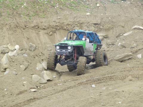 1990 Ford Bronco - A custom-built off-road buggy navigates a steep, rocky incline on a dirt trail.