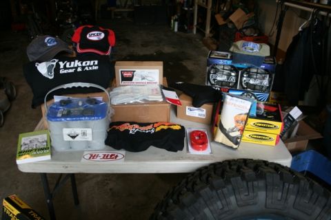 1990 Chevrolet Suburban - A collection of automotive parts and apparel are displayed on a table, with a large tire in the foreground.