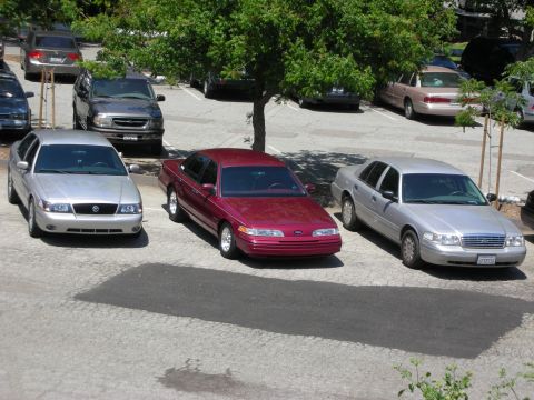 1992 Ford Crown Victoria - A maroon sedan is parked in a lot with several other vehicles visible.
