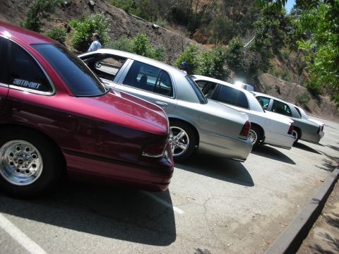 1992 Ford Crown Victoria - A line of Ford Crown Victorias are parked on a paved lot with a hillside in the background.