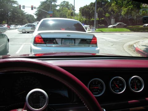1992 Ford Crown Victoria - Rear view of a white Ford Crown Victoria at an intersection, seen from the driver's perspective.