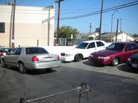 1992 Ford Crown Victoria - Three sedans, including a 1992 Ford Crown Victoria, are parked in a lot on a sunny day.