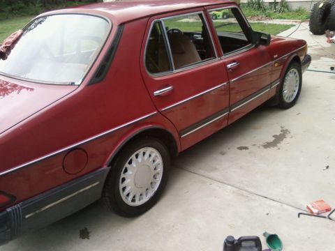 1987 Suzuki Samurai - A red sedan with chrome trim and silver hubcaps is parked on a concrete surface. The vehicle appears to be a sedan from the 1980s or 1990s.