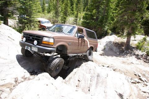 1993 Ford Bronco - This 1993 Ford Bronco is shown tackling a challenging off-road course, with a second vehicle visible in the background.