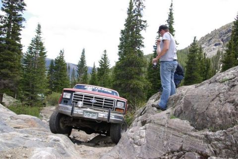 1993 Ford Bronco - Ford Bronco tackling a challenging off-road course in a mountainous, forested area.