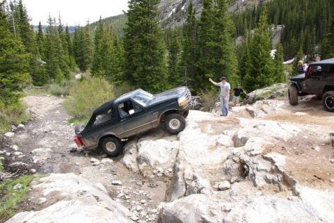 1993 Ford Bronco - A 1993 Ford Bronco tackles a challenging off-road course with other vehicles nearby.