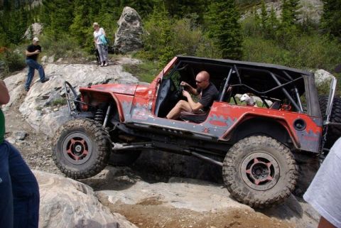 1993 Ford Bronco - This heavily modified off-road jeep is tackling a challenging rocky trail, its robust suspension and off-road capabilities.