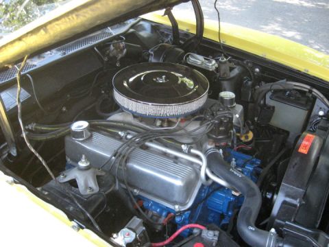 1972 Ford Ranchero - The engine bay of a yellow vehicle, a V8 engine with a chrome air cleaner and visible hoses and wiring.