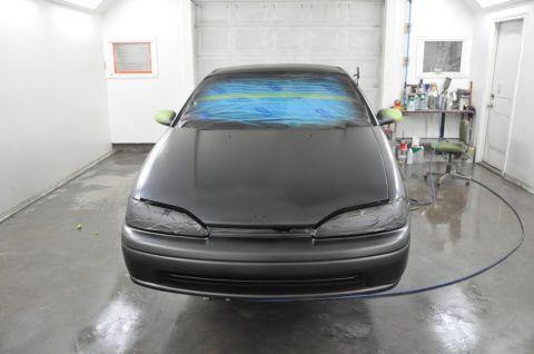 1996 Ford Bronco - A car is prepared for painting in a booth, with the windshield and headlights covered.