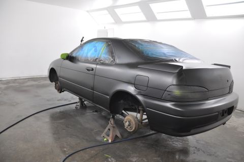 1996 Ford Bronco - A coupe is being prepped for painting inside a spray booth, with its wheels removed and windows covered.