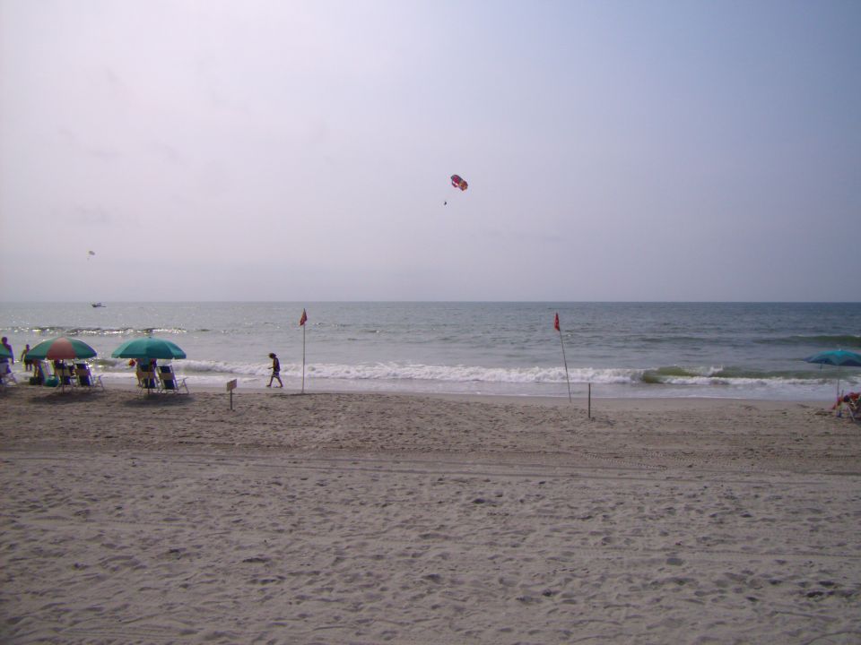 Beach scene with parasailing and umbrellas