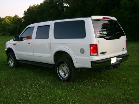 2000 Ford Excursion - Rear 3/4 view of a white 2000 Ford Excursion parked on a grassy lawn with trees in the background.
