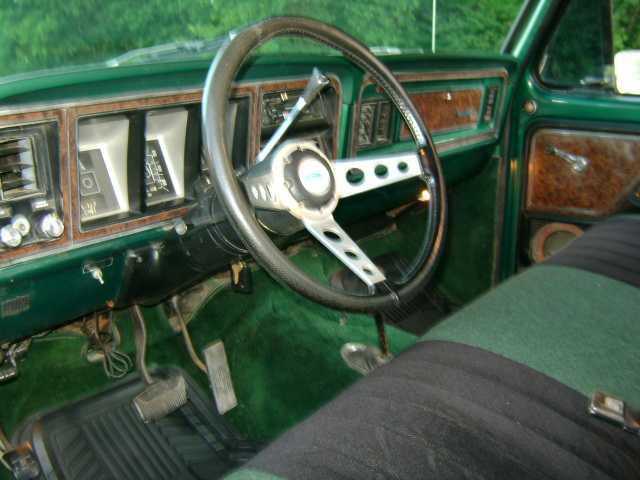 Green interior of a truck, showing the steering wheel, dashboard, and seat