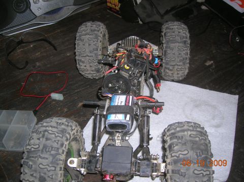 1985 Ford Bronco - RC crawler chassis with battery and wiring, viewed from above on a wooden surface.