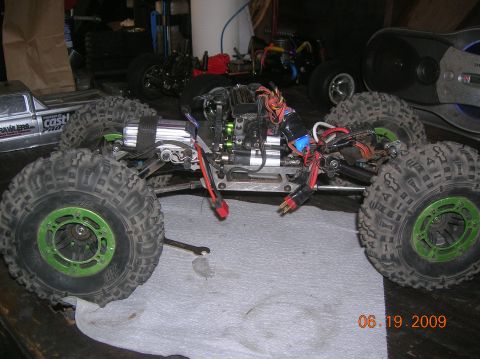 1985 Ford Bronco - An RC crawler with prominent green wheel rims and visible wiring is shown on a workbench.