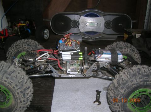 1985 Ford Bronco - RC crawler chassis with large tires and visible electronics, another RC car in background.
