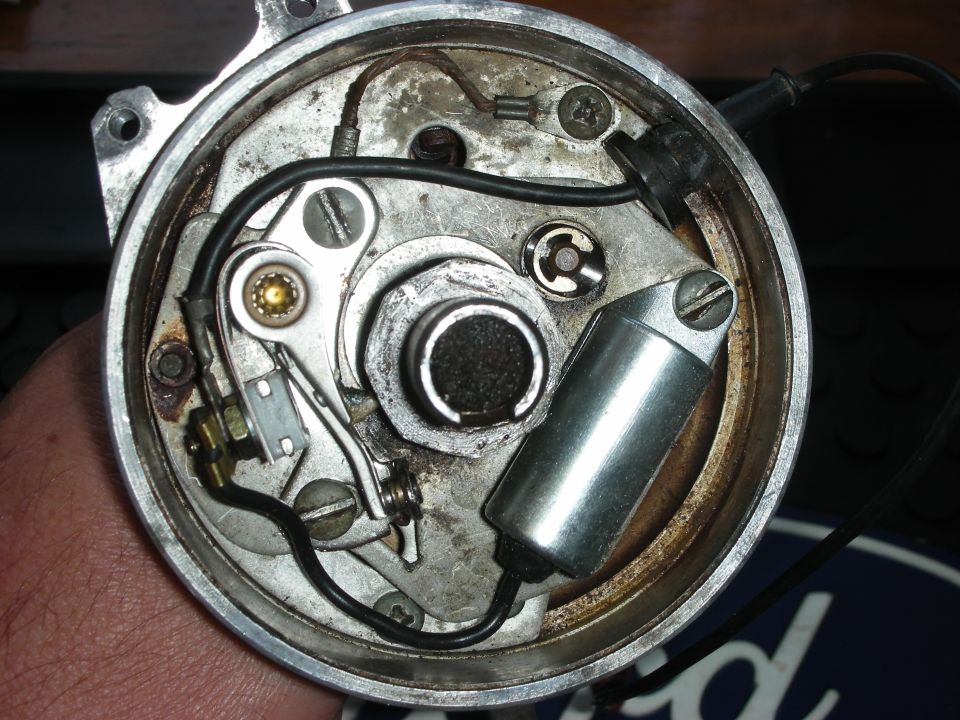 Close-up of a car's distributor cap interior, showing points, condenser, and rotor mechanism