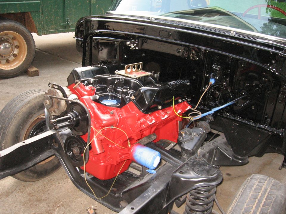 Red engine block and black chassis components of a truck, with a tire visible on the left
