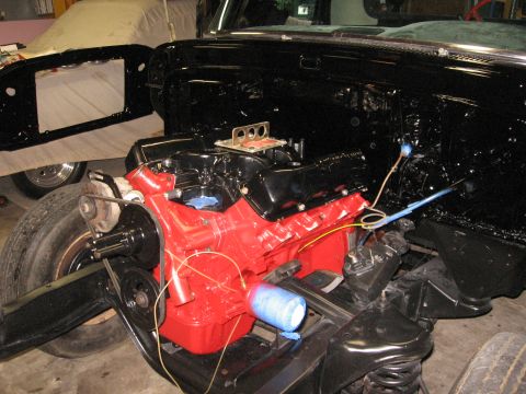 1966 Ford F-100 - The engine bay of a truck is shown during reassembly, with the red engine prominently displayed.