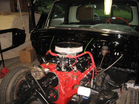 1966 Ford F-100 - The engine bay of a classic truck is shown with a freshly painted red V8 engine and black components.