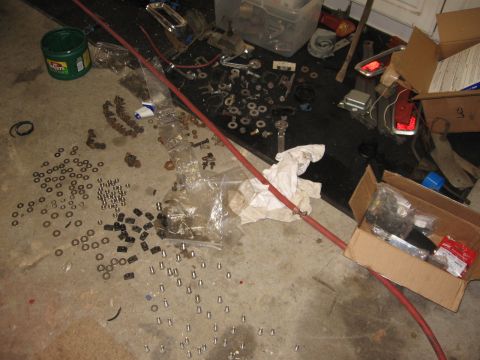 1966 Ford F-100 - A collection of disassembled vehicle components and hardware are spread across a garage floor.