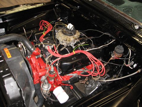1966 Ford F-100 - Close-up view of a vehicle's engine bay, highlighting the red spark plug wires and black engine components.