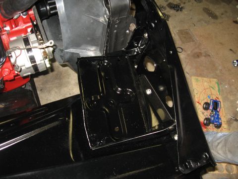 1966 Ford F-100 - Close-up view of vehicle frame and engine components during re-assembly, with a toy truck in the background.