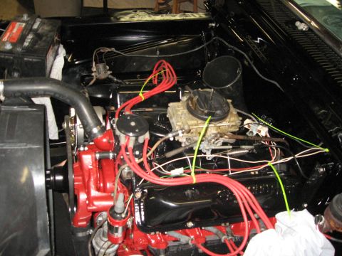 1966 Ford F-100 - Close-up view of a vehicle's engine bay, highlighting the red water pump and black engine block with red spark plug wires.