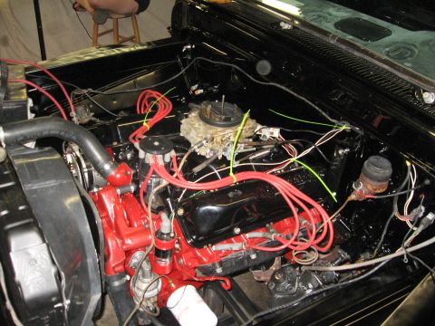 1966 Ford F-100 - Close-up of a V8 engine in a black engine bay, red components and wiring.