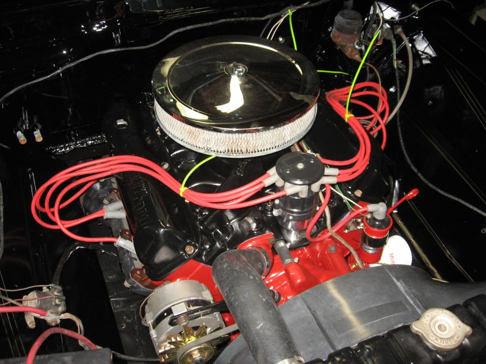 Engine bay with red spark plug wires, chrome air cleaner, and black valve covers