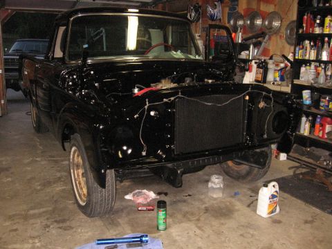 1966 Ford F-100 - A black 1956 Ford F-100 truck is partially disassembled in a garage, with tools and supplies nearby.