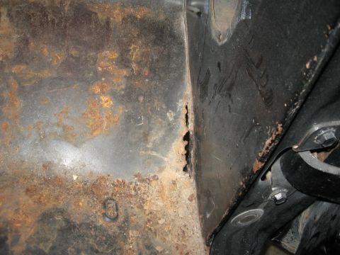 1966 Ford F-100 - Close-up view of a corroded metal panel, revealing significant rust damage and a hole.