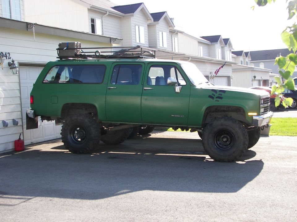 Green lifted SUV with roof rack parked in driveway