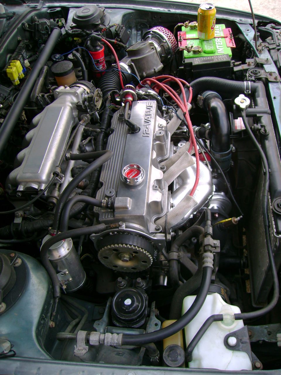 Engine bay with a 12-valve engine, aftermarket air intake, and a can of soda on the battery